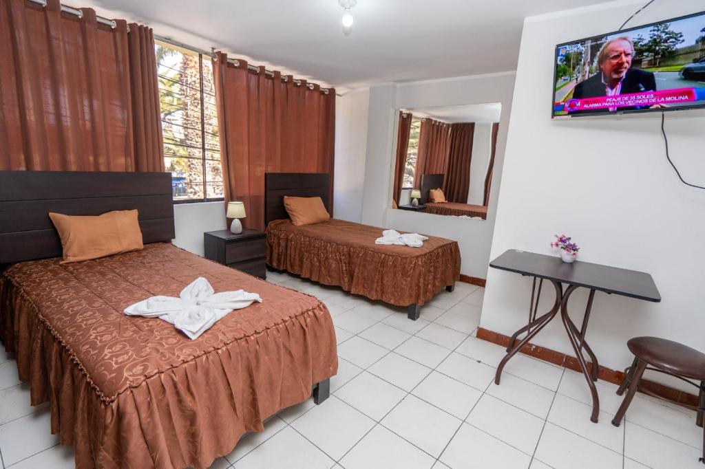 a hotel room with two beds and a flat screen tv at Hotel Residencial C´BASTIAN in Tacna