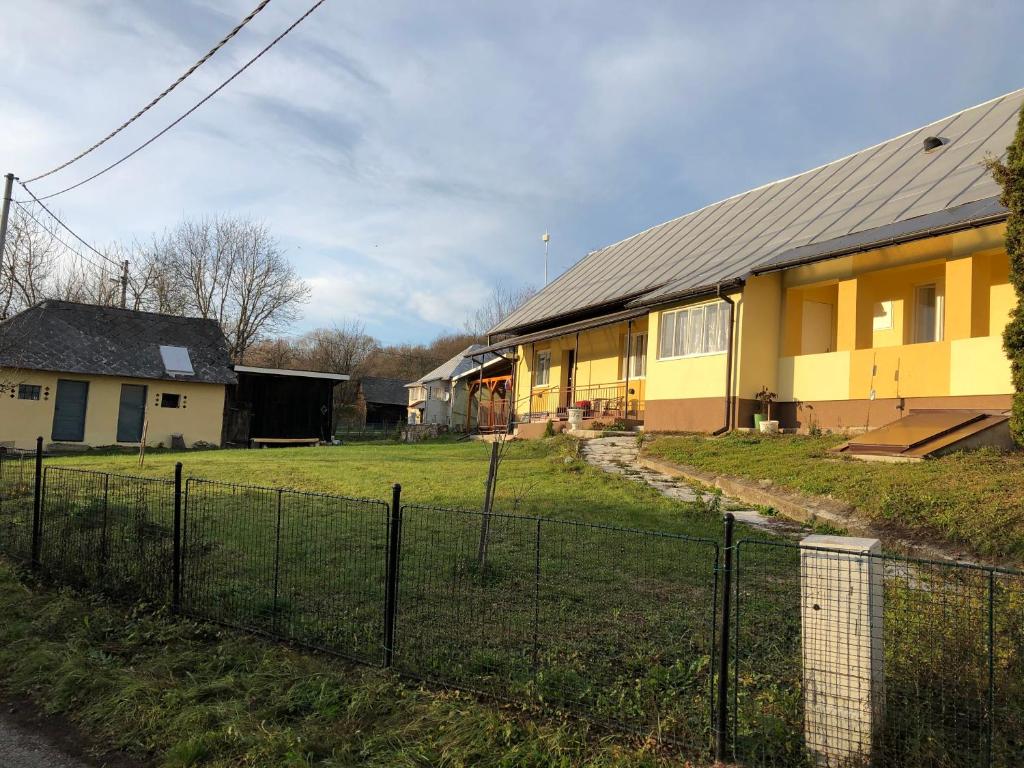 um edifício amarelo com uma cerca em frente em Usadlosť pri lúke em Mlynárovce