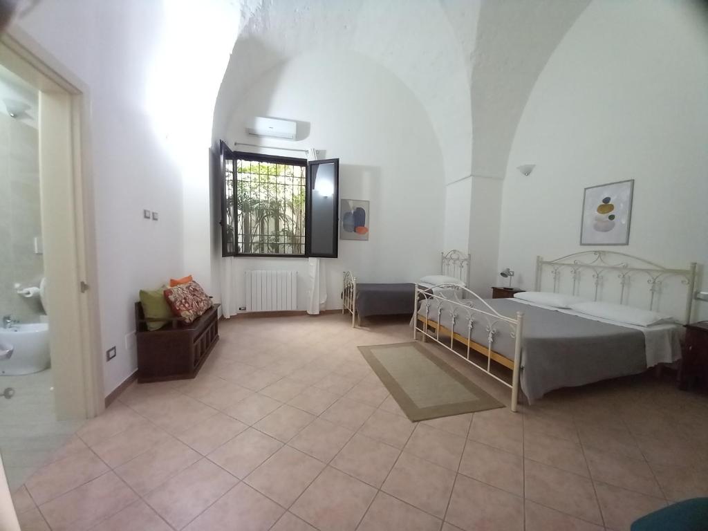Großes Zimmer mit 2 Betten und einem Fenster in der Unterkunft Le antiche volte del 1900 in Galatone