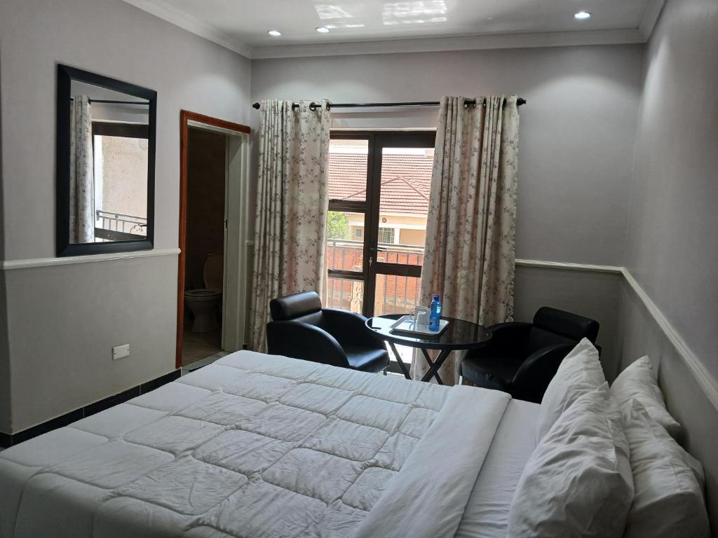 a bedroom with a bed and chairs and a window at FourPoints Lodge in Lilongwe