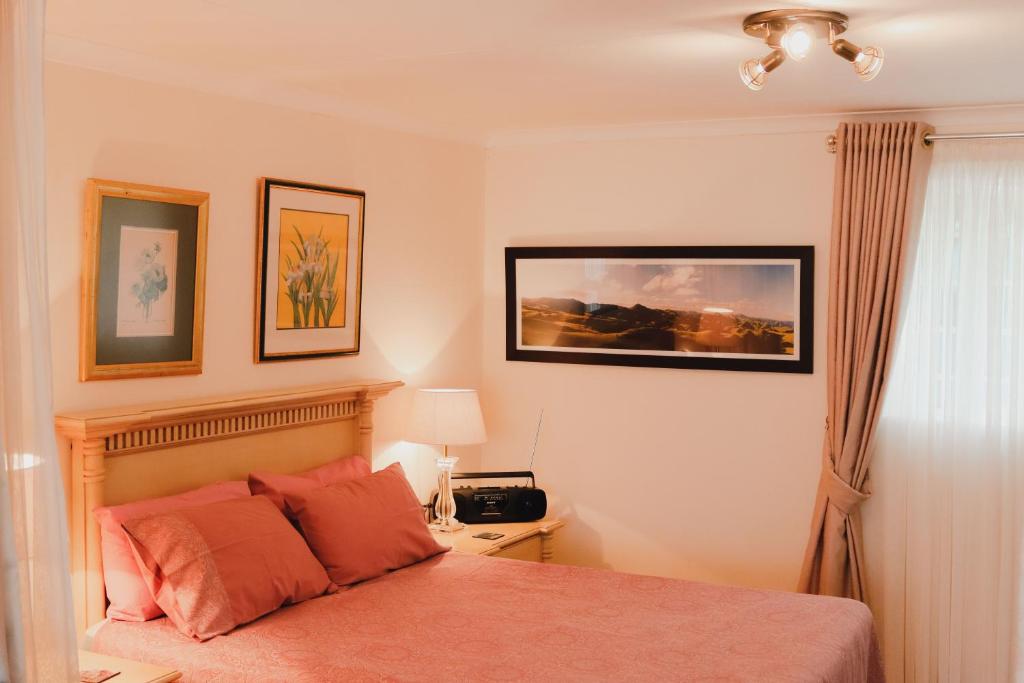 a bedroom with a bed and a night stand with a lamp at Vista Garden Cottage in Mbabane