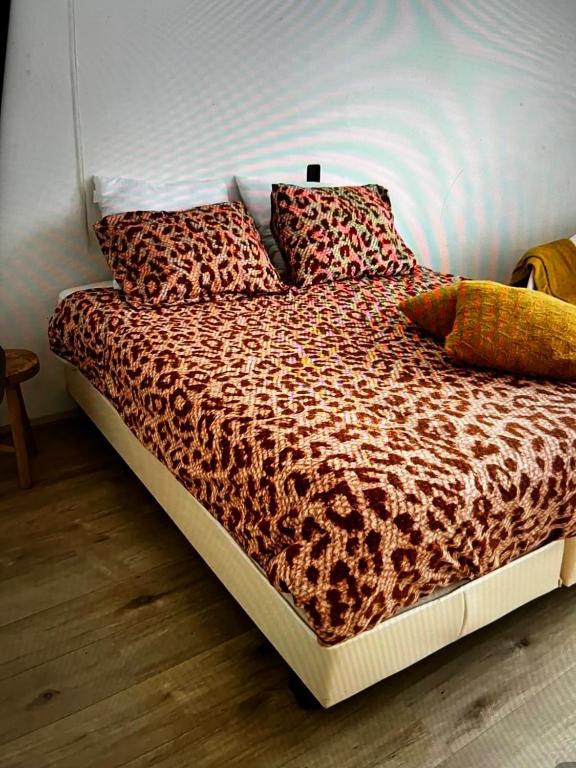 a bed with a leopard print blanket and pillows at Appartement Zuiderzeestate Makkum in Makkum