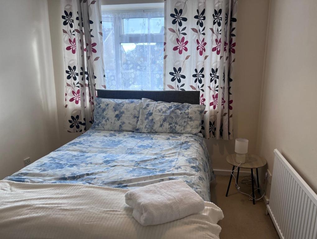 a bed in a bedroom with curtains and a window at Newport Pagnel Guest house in Buckinghamshire