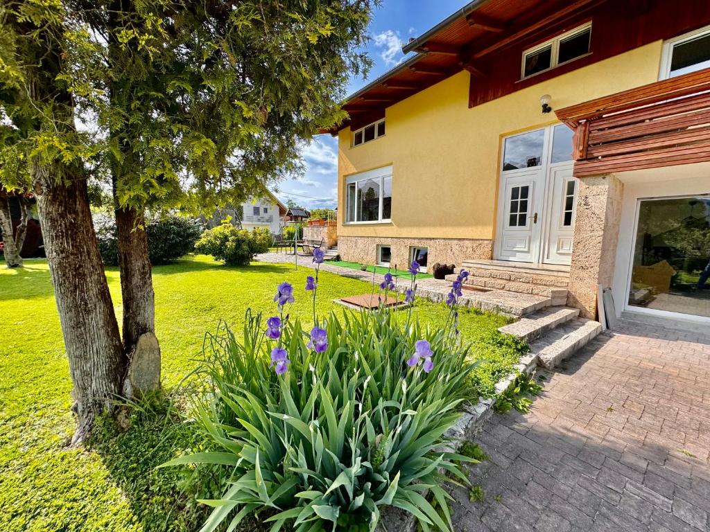 una casa con flores púrpuras en el patio en Hiša Naomi Sofia, en Bled
