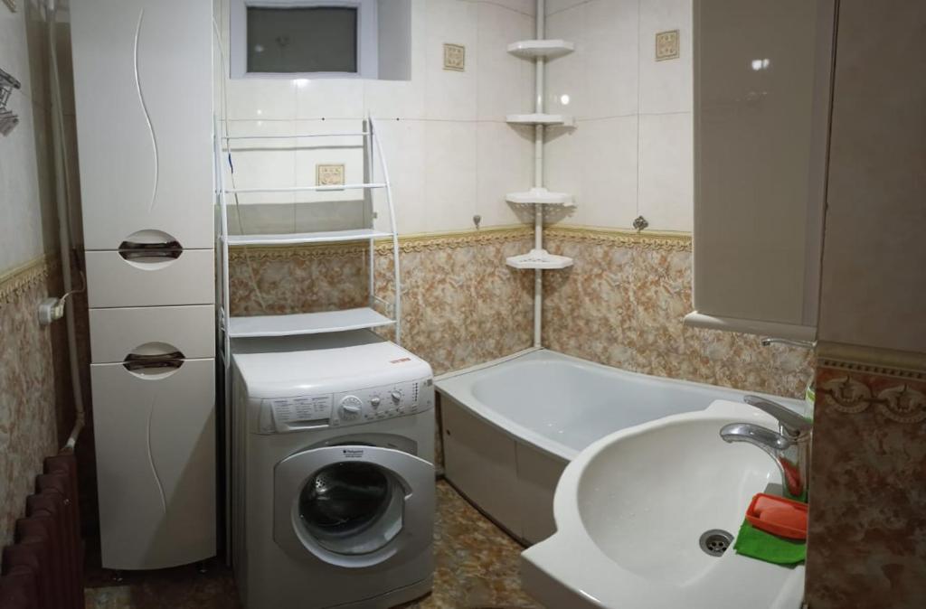a small bathroom with a washing machine and a bath tub at Трешка Саулет 11 in Qyzylorda