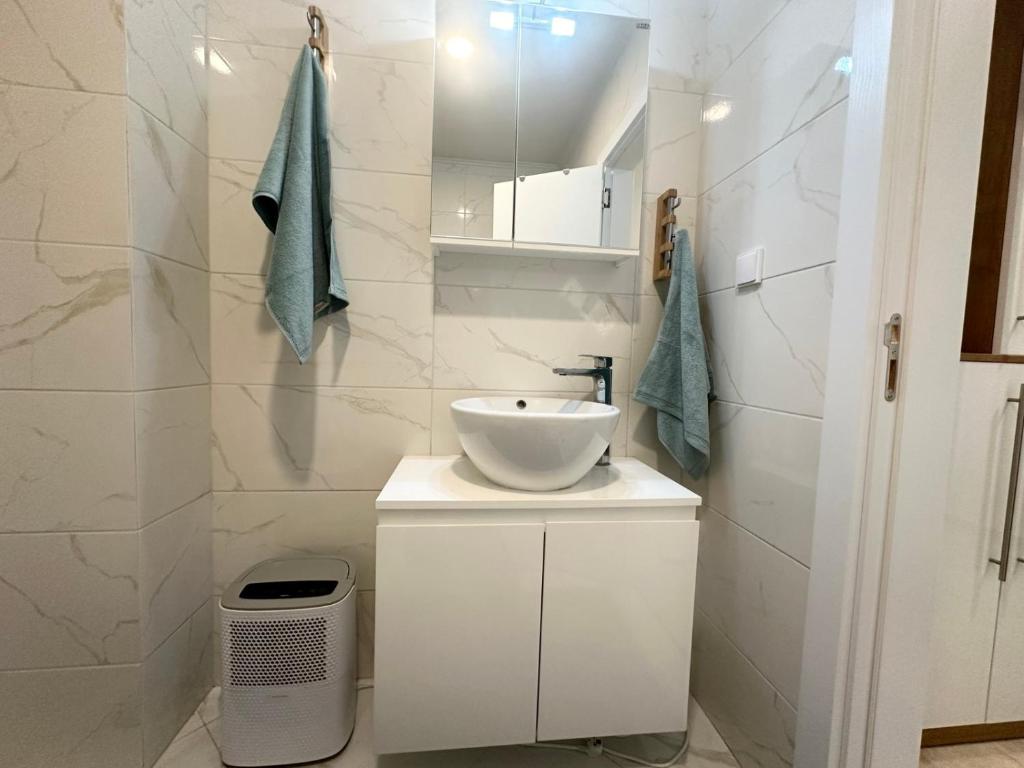 een witte badkamer met een wastafel en een spiegel bij Pool apartment on the beach in Boergas