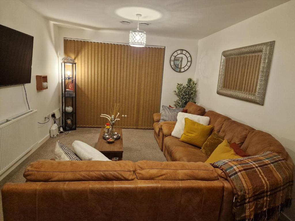 a living room with a brown couch and a table at A stunning room in a 2 bed apartments in the heart of Medway in Gillingham