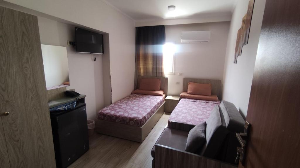 a small room with two beds and a television at فندق أجياد Agyad Hotel in Asyut