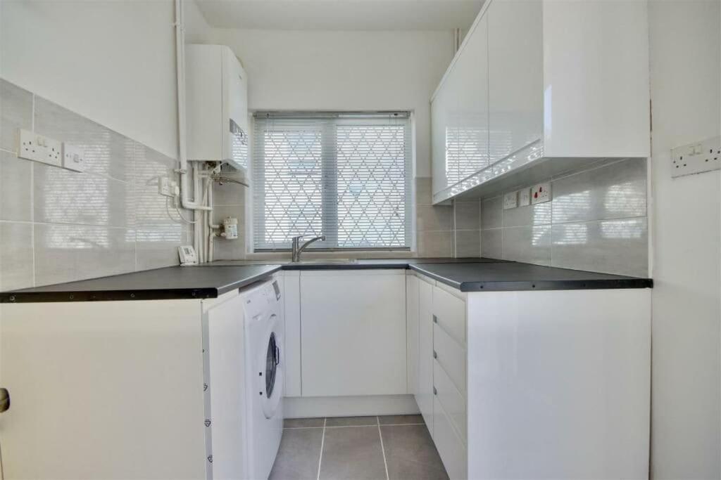 a white kitchen with white cabinets and a sink at Newly renovated private house in Portsmouth