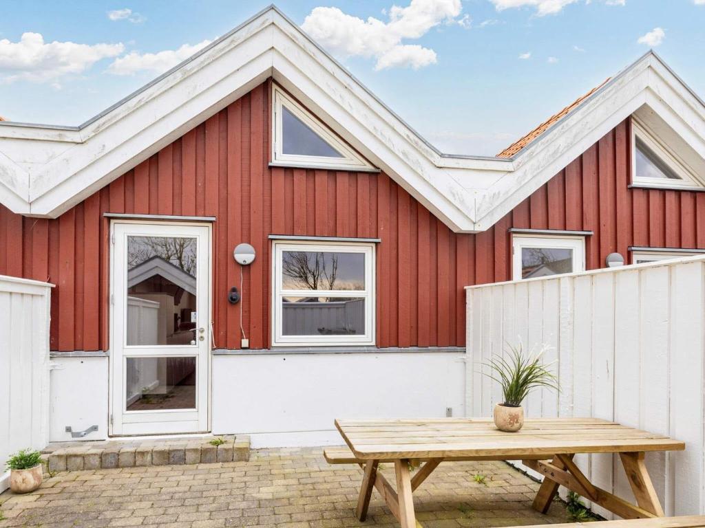 a red house with a white fence and a picnic table at 4 person holiday home in Nibe in Nibe