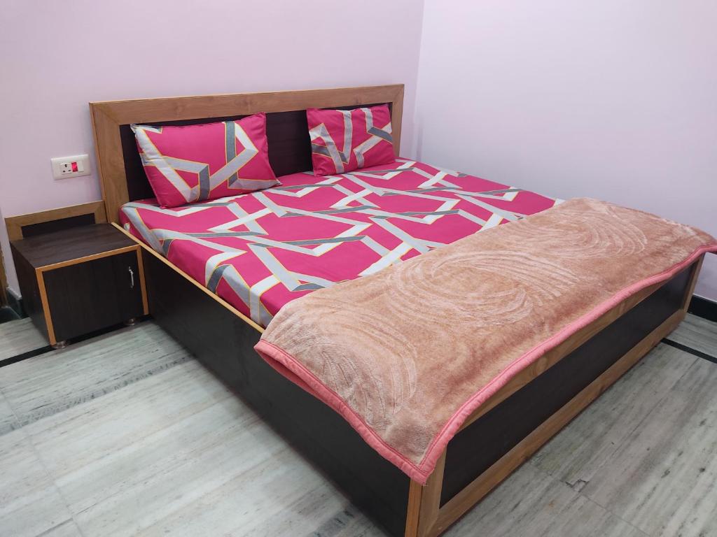 um quarto com uma cama grande com lençóis cor-de-rosa e brancos em Nature's Paradise Homestay em Haridwar