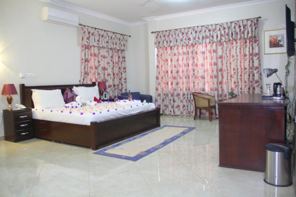 a bedroom with a bed and a desk in it at Gold Plus Hotel Ghana in Kumasi