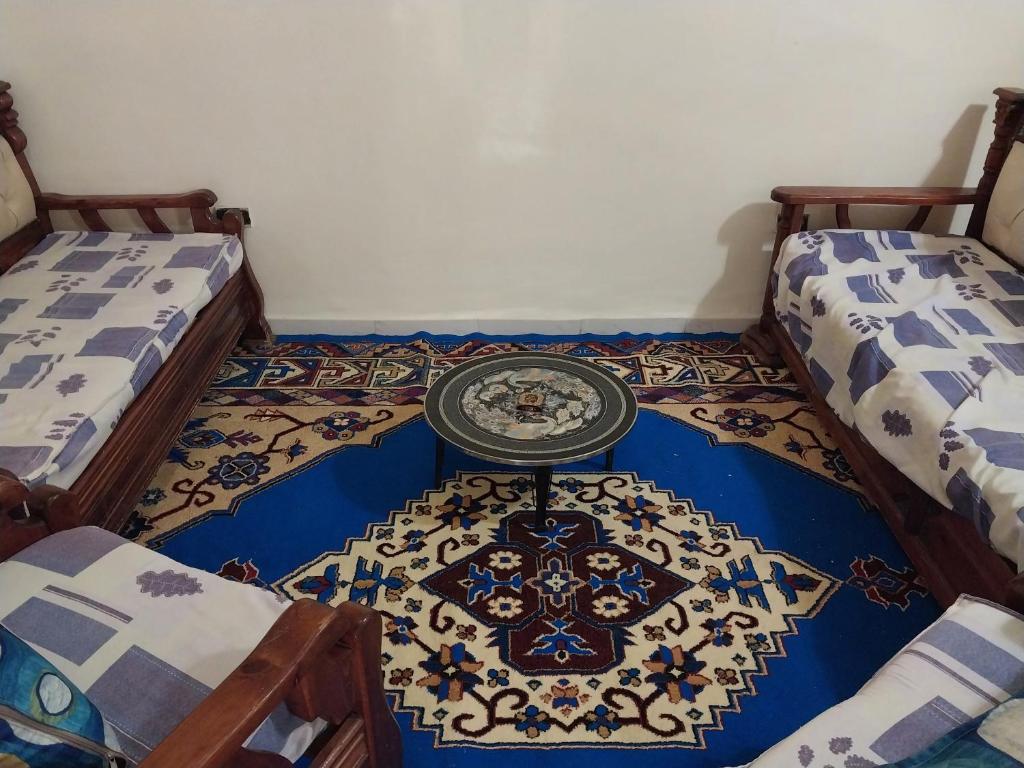 Cette chambre comprend 2 lits et une table sur un tapis. dans l'établissement Brooklyne, à Tunis