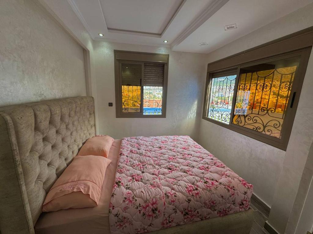 ein Schlafzimmer mit einem Bett und zwei Buntglasfenstern in der Unterkunft Duplex panoramique avec jardin in Chefchaouen