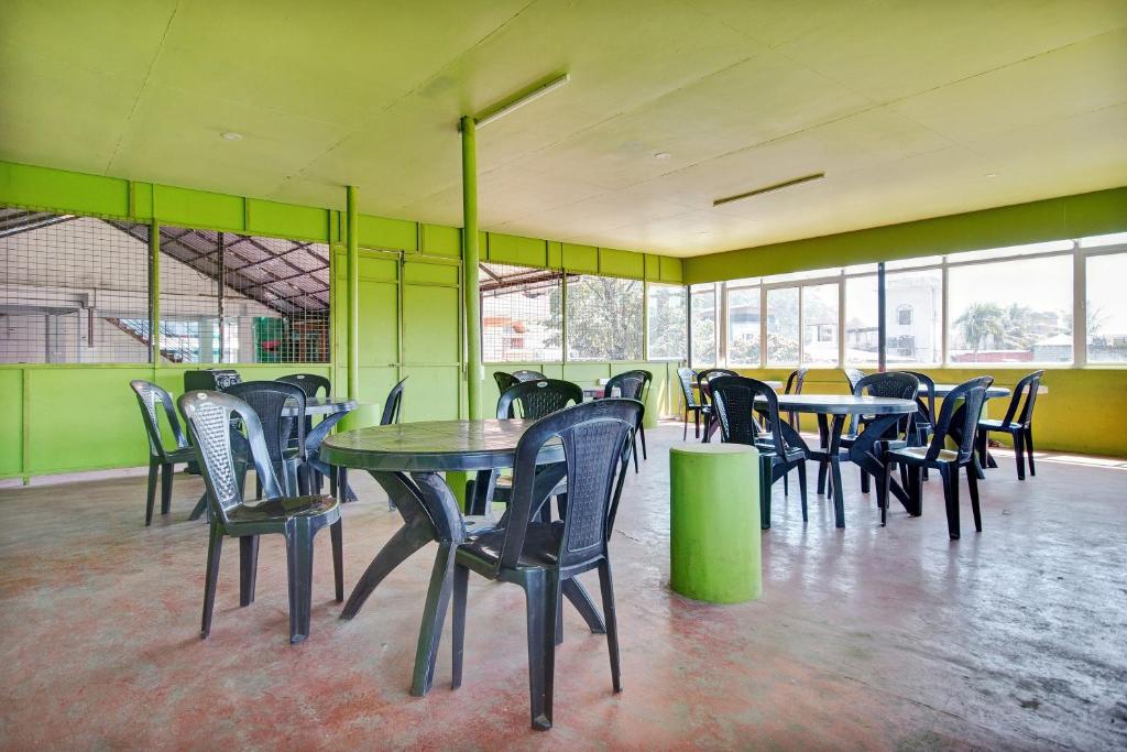 una sala da pranzo con tavoli, sedie e finestre di Collection O Prashant Stays a Trippapur