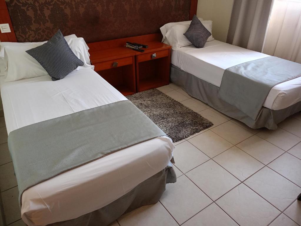 two beds in a hotel room with a table at Hôtels Jardy in Bab Ezzouar