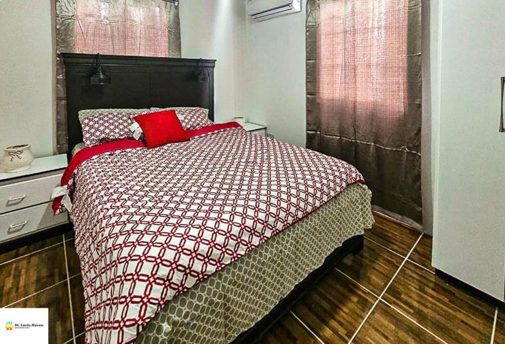 a bedroom with a bed with red pillows on it at Ces’t Lavie ultra apartments in Gros Islet