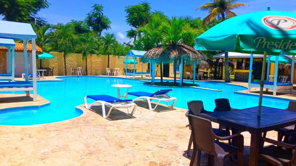 a pool with chairs tables and umbrellas at El Currican Juan Dolio in Juan Dolio
