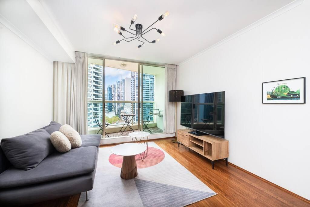 a living room with a couch and a tv at CBD Sydney - KING Suite Sussex St 2 Room 1 Parking in Sydney