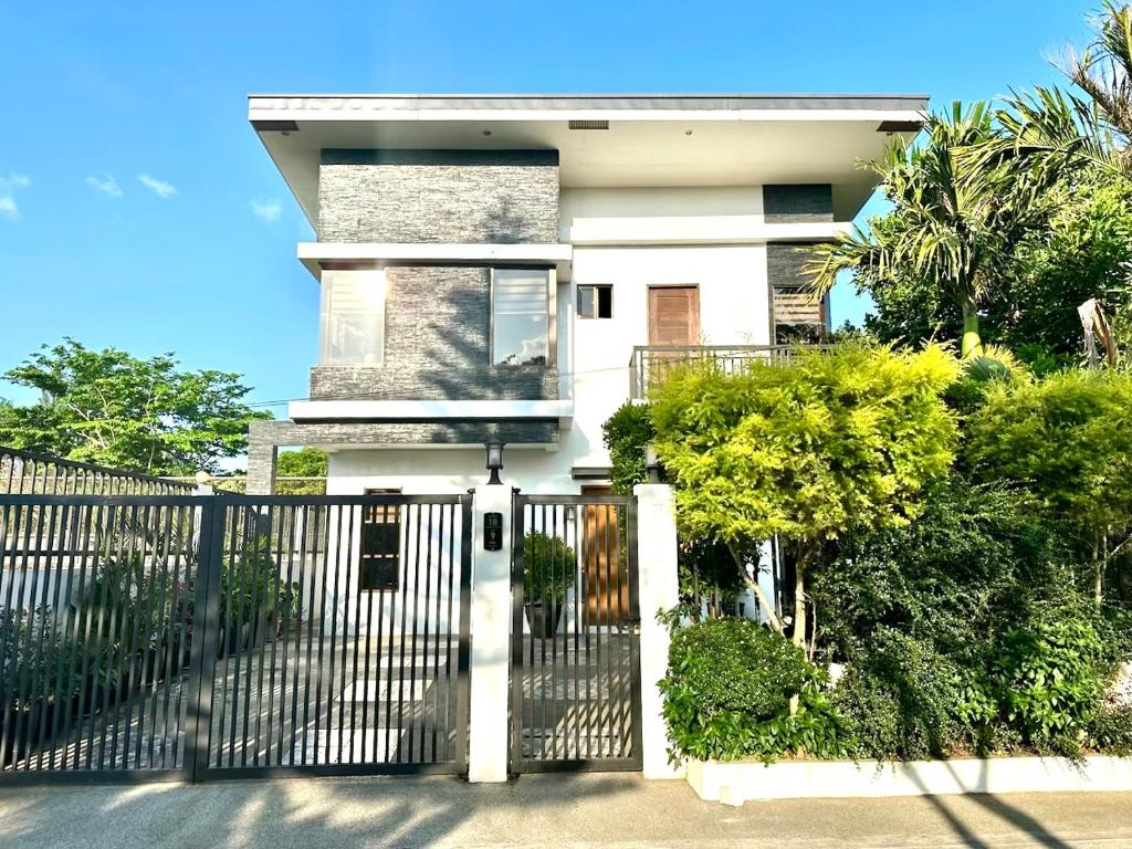 Biały dom z bramą i krzakami w obiekcie Bella Homes 6BR 4Bath near Rotunda w mieście Tagaytay