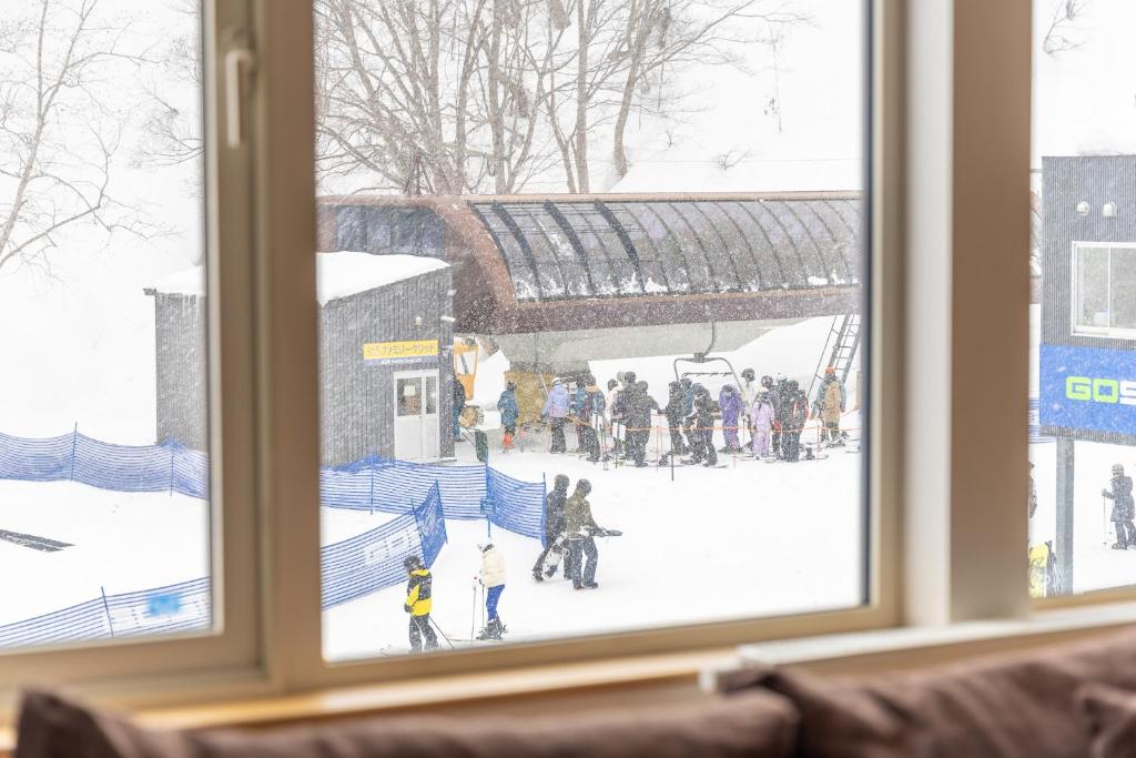 倶知安町にあるChalet Murasakiの雪の中の人々の姿が見える窓