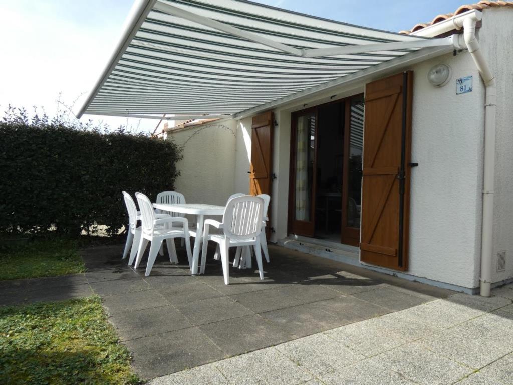 une terrasse avec une table et des chaises sous un parasol dans l'établissement Maison de Vacances avec Piscine, Plage à 1 km, Wifi, 5 pers – Notre-Dame-de-Monts - FR-1-540-289, à Notre-Dame-de-Monts