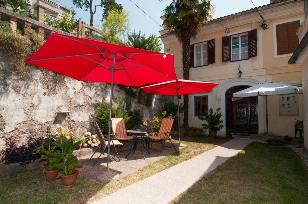 two red umbrellas in the yard of a house at Apartment Villa Minach in Volosko