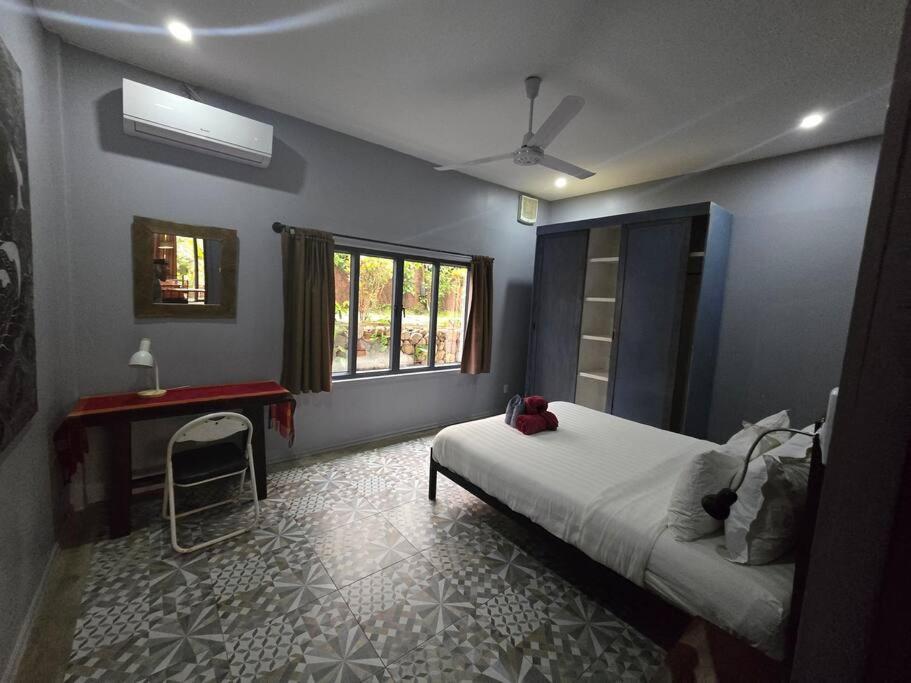 1 dormitorio con cama, escritorio y ventana en #5 Appartement meublé + piscine., en Luang Prabang