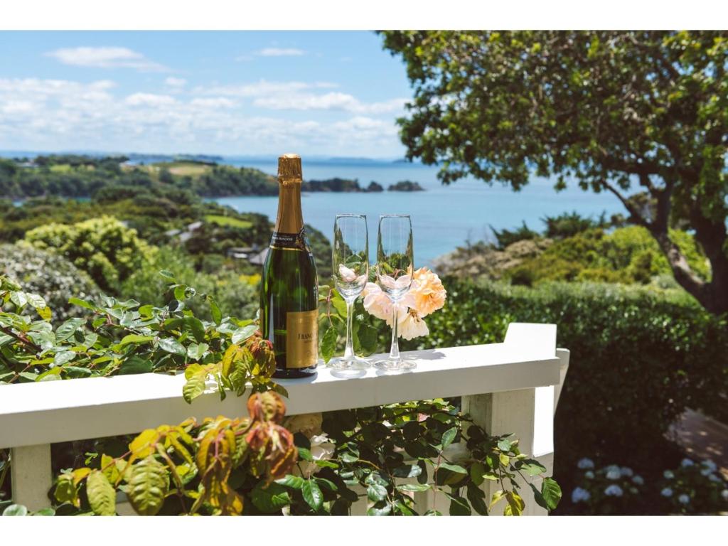 a bottle of champagne and glasses on a white bench at Romantic Cottage Recommended by NZ Herald in Oneroa