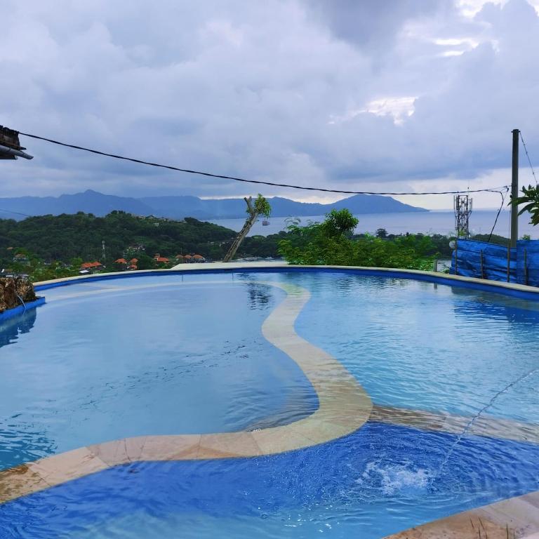 a large blue swimming pool with mountains in the background at Yoga bale house in Padangbai
