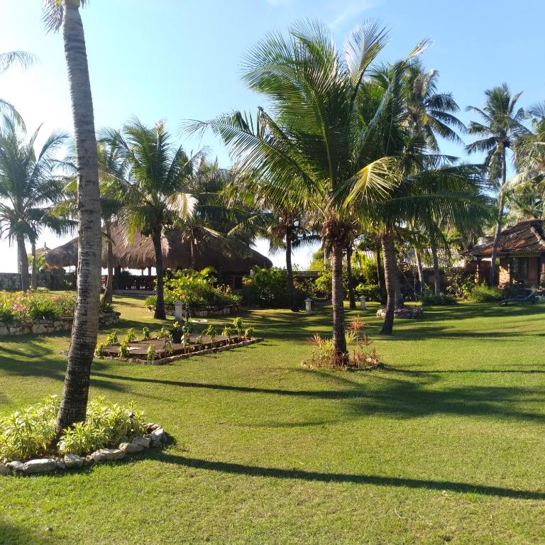 a park with palm trees and green grass at Villa Sedeoen in Nembrala