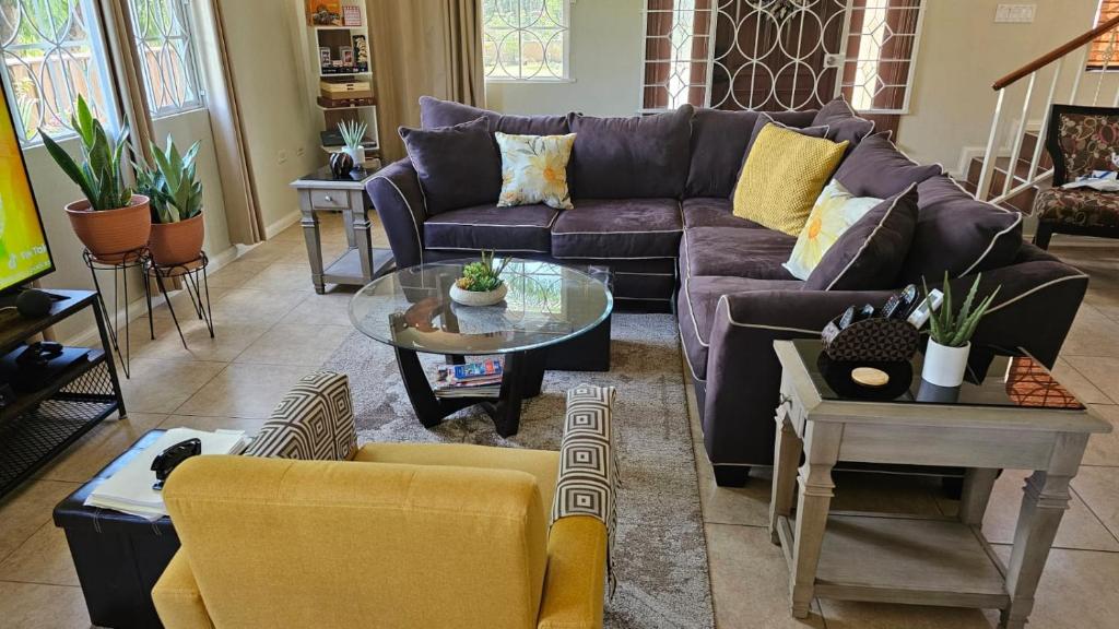 sala de estar con sofá púrpura y mesa en Komfort Getaway Villa, en Ocho Ríos