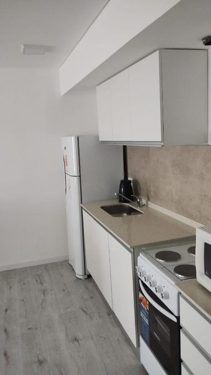 a kitchen with white cabinets and a stove top oven at Depto moderno a estrenar!!! in Comodoro Rivadavia