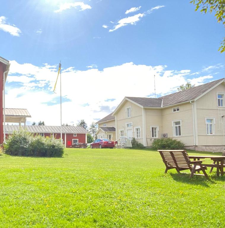 a park bench sitting in the grass in front of a house at Liepeen pappila in Pudasjärvi