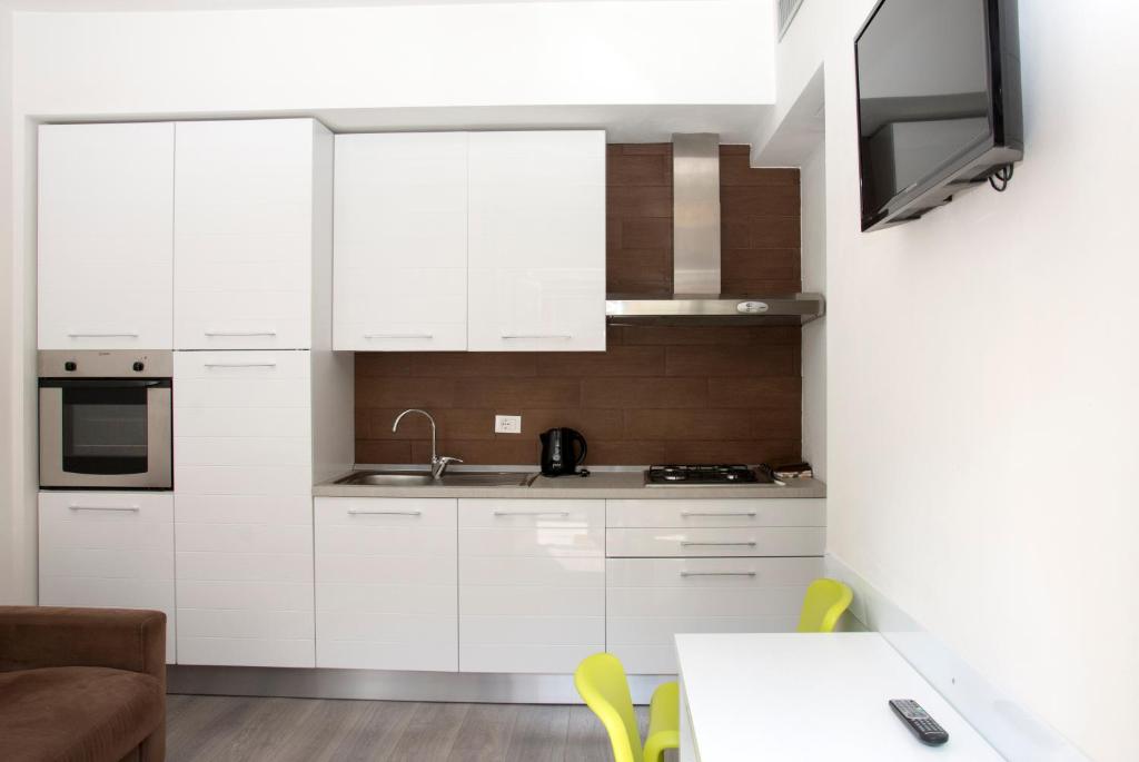 a kitchen with white cabinets and a table with yellow chairs at casa vacanza dovevai in Bergamo