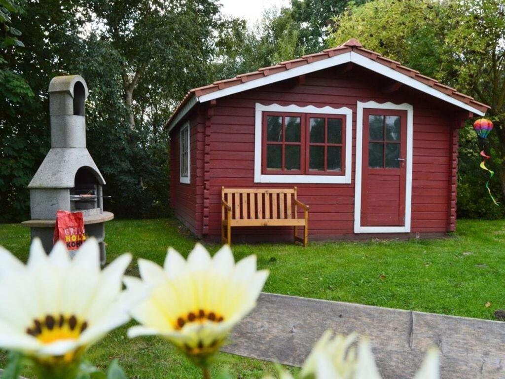 un cobertizo rojo con un banco en un patio en Deichjuwel Comfortable holiday residence en Norddeich