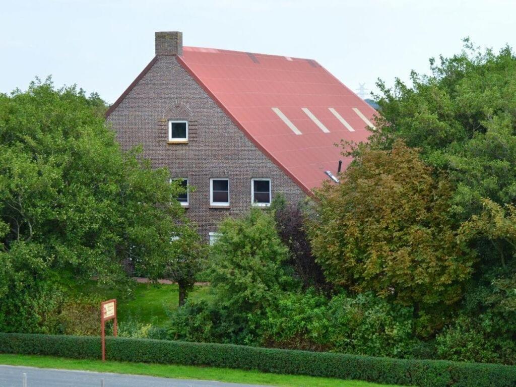 une grande grange rouge avec un toit rouge dans l'établissement Deichstübchen Comfortable holiday residence, à Norddeich