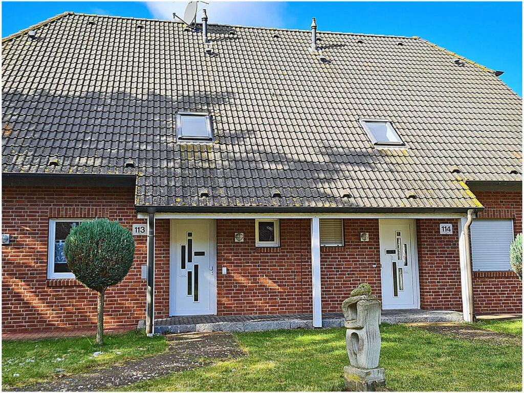 ブレーゲにあるPatricia Comfortable holiday residenceの白い扉と木のある赤レンガ造りの家