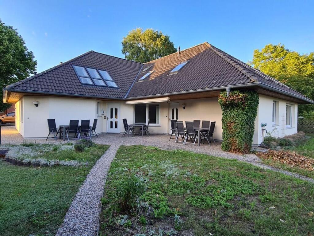 a white house with chairs and a yard at Earth Comfortable holiday residence in Ostseebad Koserow