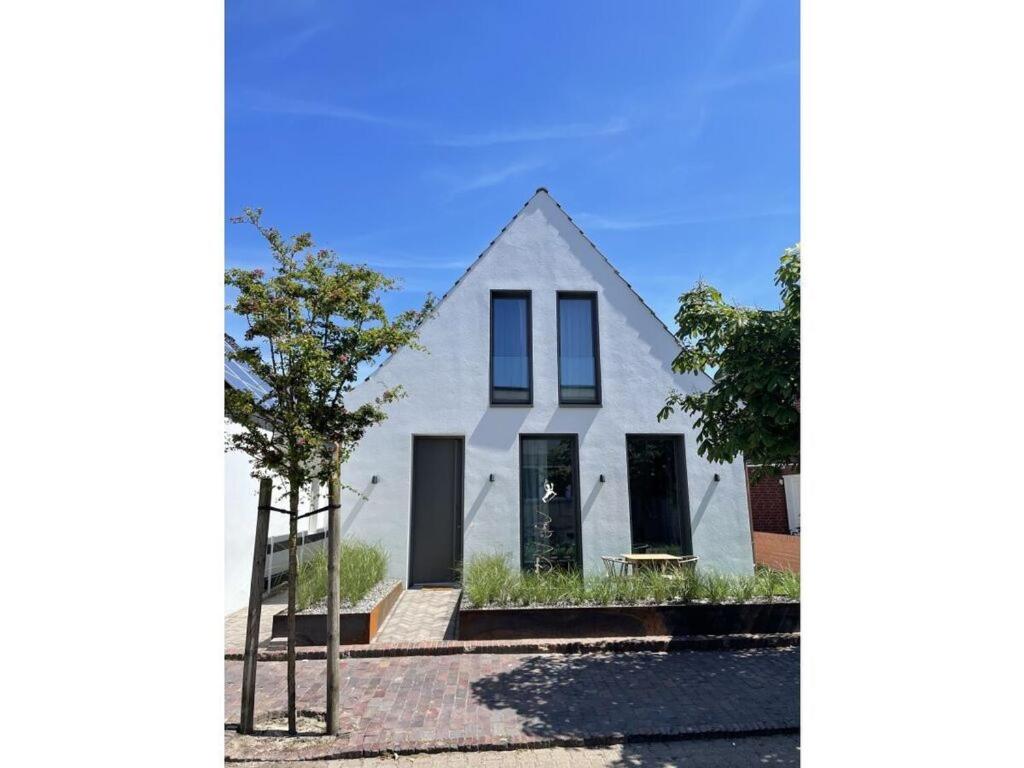 uma casa branca com janelas pretas e uma árvore em Mooi 3 Comfortable holiday residence em Norderney