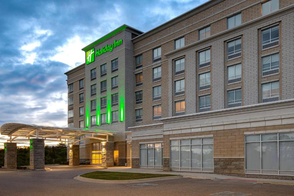 un bâtiment d'hôtel avec un panneau vert dans l'établissement Holiday Inn Detroit Northwest - Livonia, an IHG Hotel, à Livonia