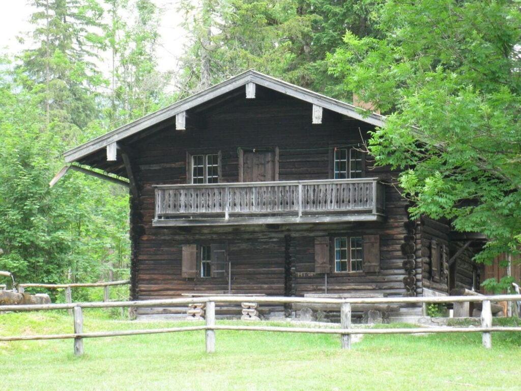 a log cabin with a porch and a balcony at Klausenberg Hausberg - Gästehaus am Maibaum in Reit im Winkl