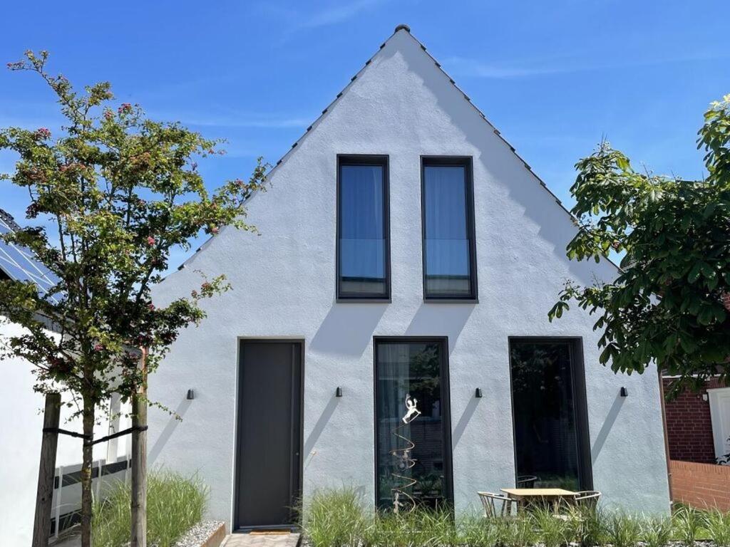 una casa con ventanas negras y fachada blanca en Mooi 2 Comfortable holiday residence en Norderney