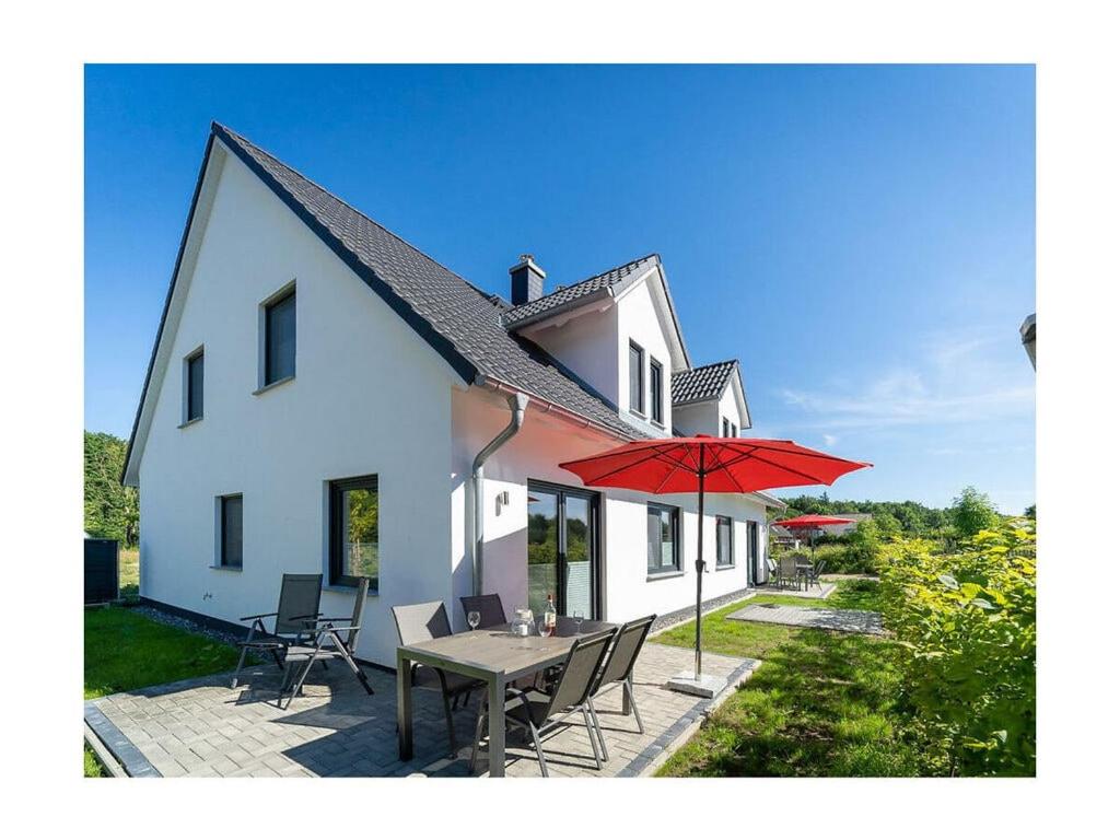 a white house with a table and a red umbrella at Meerzeit Comfortable holiday residence in Juliusruh