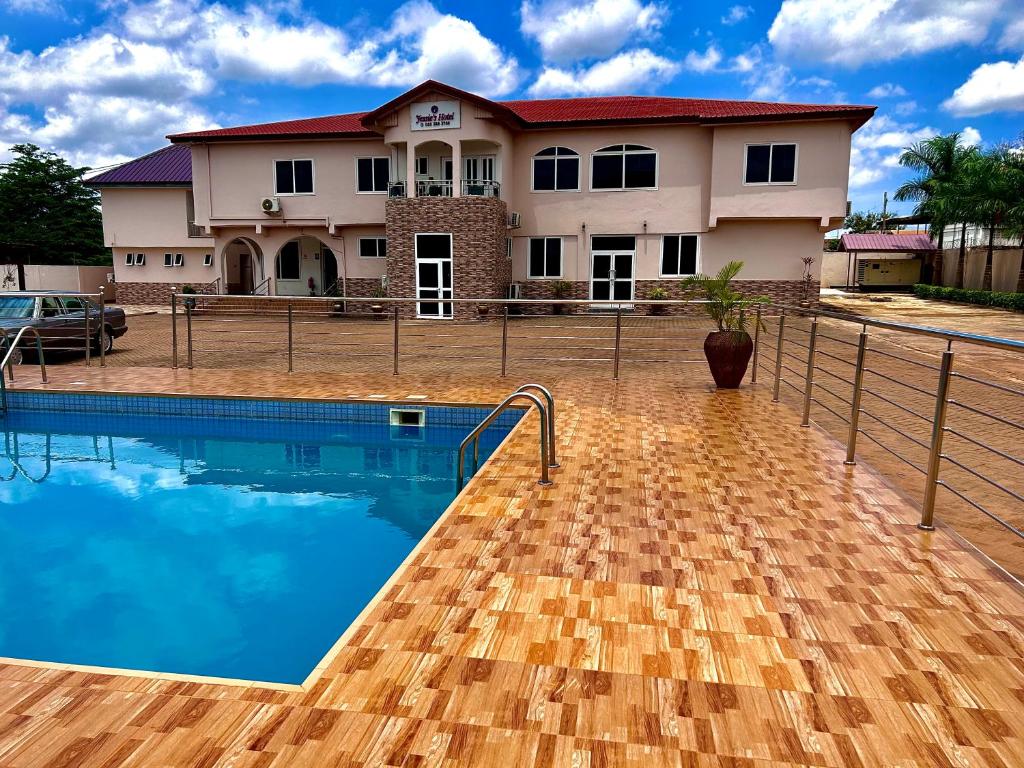 uma casa com piscina em frente a uma casa em Jessie Hotel em Apenkwa