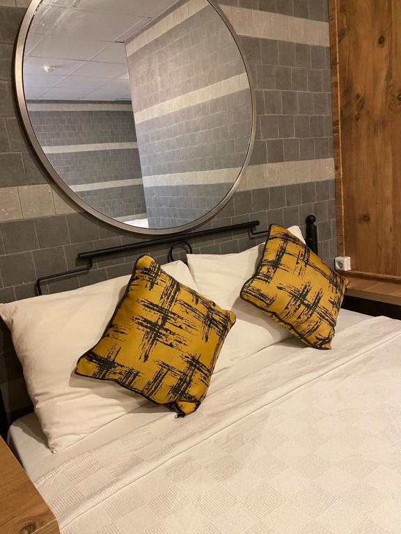 1 cama con 2 almohadas amarillas y espejo en M-ODA OTEL, en Antalya