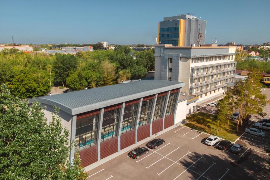 an office building with cars parked in a parking lot at Cosmonaut in Karagandy