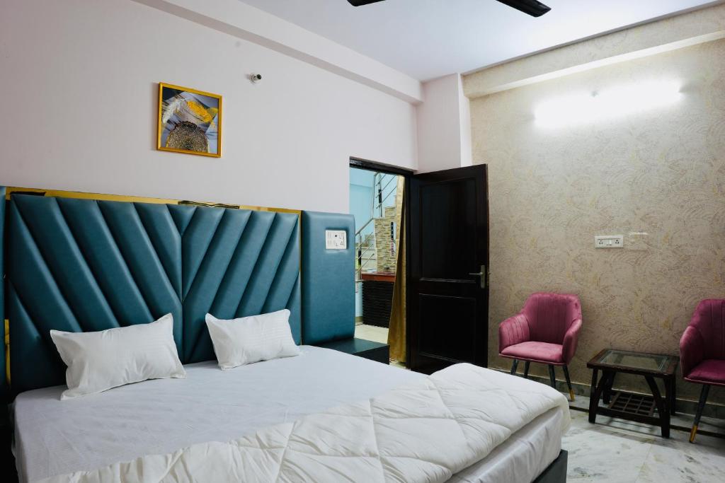 a bedroom with a bed and two pink chairs at BLISS STAYS in Rishīkesh