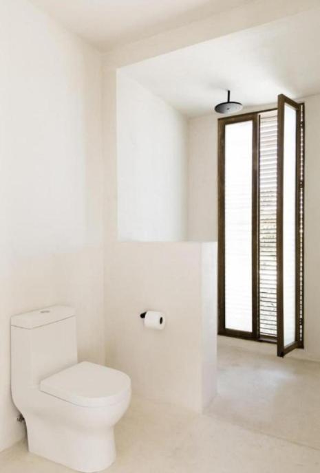 a white bathroom with a toilet and a window at Kalibo getaways airport in Numancia
