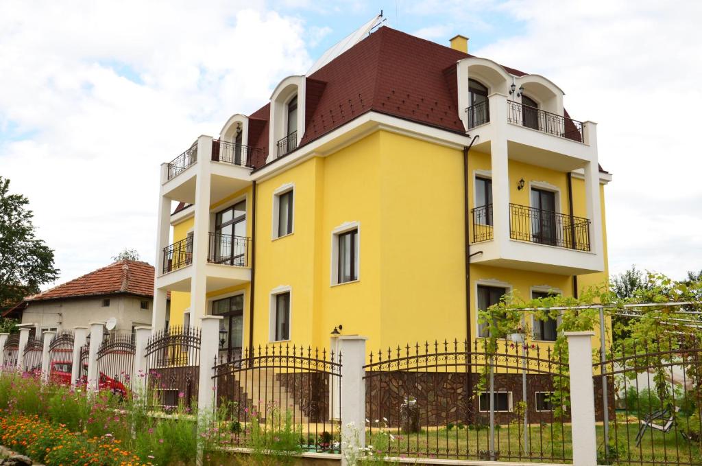 een geel en wit gebouw met een rood dak bij Guest House Nocturno in Berkovitsa
